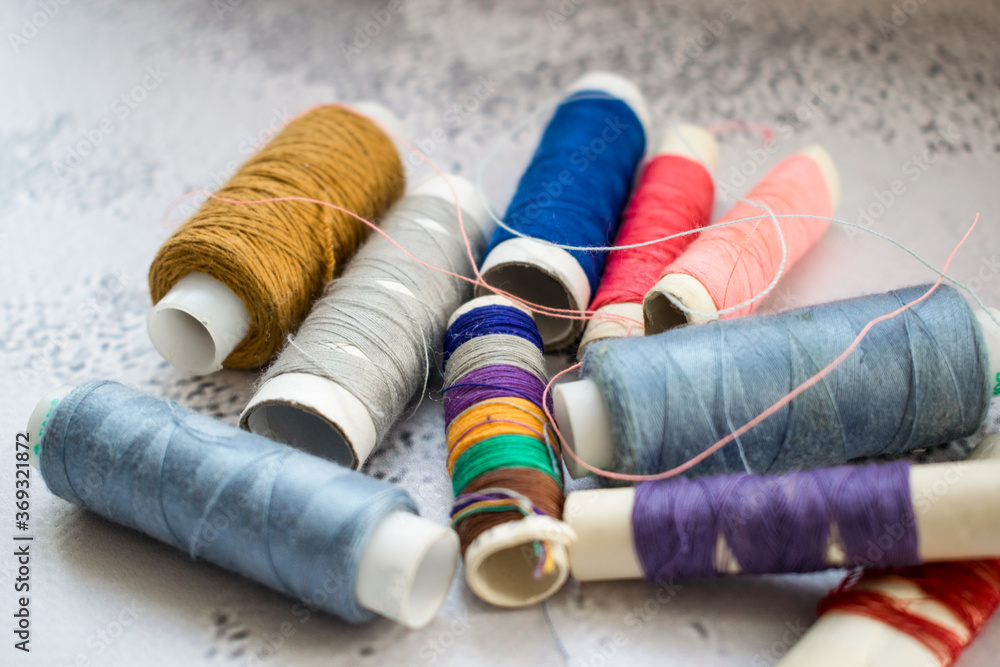 Multicolored spools of thread on light background. Threads close up Multicolored spools of thread on light background. Threads close up