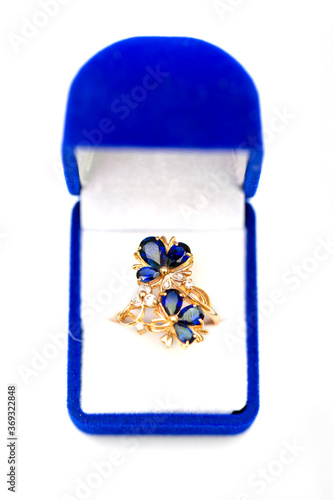 Gold ring with blue sapphires and cubic zirkonia in gift box on white background