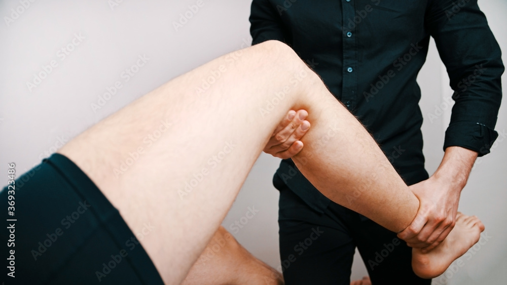 Young man having his knee examined by specialist. Physiotherapy knee flexibility. High quality photo
