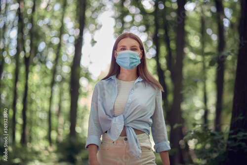 Protection during a pandemic. Young girl in a medical mask in the park.