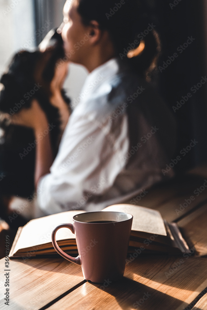 Yoman sitting in living room with her cute Bernese Mountain Dog dog, reading and drinking coffee. Yoman sitting in living room with her cute Bernese Mountain Dog dog, reading and drinking coffee.