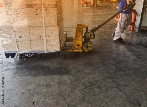 Worker driving forklift loading and unloading shipment carton boxes and goods on wooden pallet from container truck to warehouse cargo storage in logistics and transportation industrial 