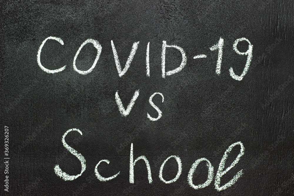 Fototapeta premium COVID-19 against school is written on a blackboard in white chalk.