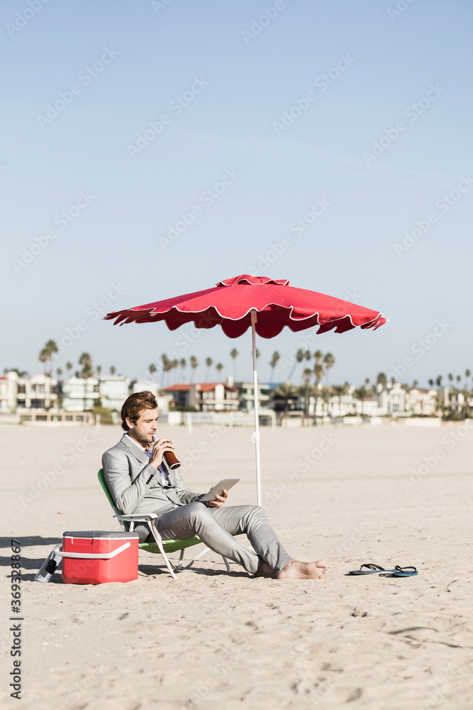 Businessman with digital tablet working on sunny beach, Los Angeles, California Businessman with digital tablet working on sunny beach, Los Angeles, California