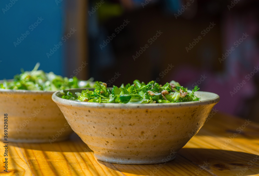 Greens and tuna salad in a ceramic bowl on a wooden table. Greens and tuna salad in a ceramic bowl on a wooden table.