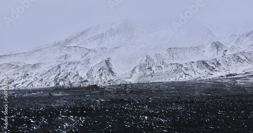 Antarctica, deception island, ruin in storm, snow on volcanic black stone