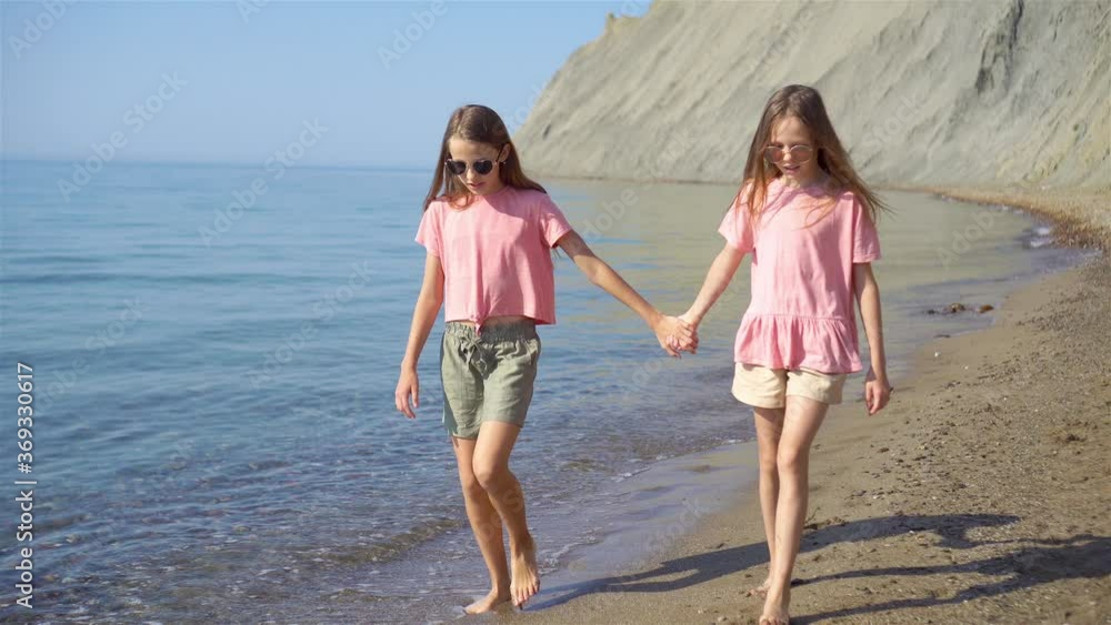Little happy funny girls have a lot of fun at tropical beach playing together. Little happy funny girls have a lot of fun at tropical beach playing together.