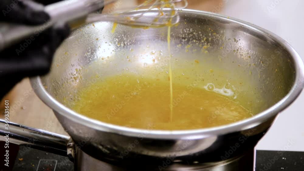 Close up of chef stirring the butter and egg yolks, holding the bowl over a pan of boiling water for heating the mixture. 4K Close up of chef stirring the butter and egg yolks, holding the bowl over a pan of boiling water for heating the mixture. 4K