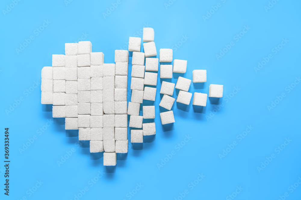 Broken heart of pure white sugar cubes on a blue background, the world day of struggle against diabetes Broken heart of pure white sugar cubes on a blue background, the world day of struggle against diabetes