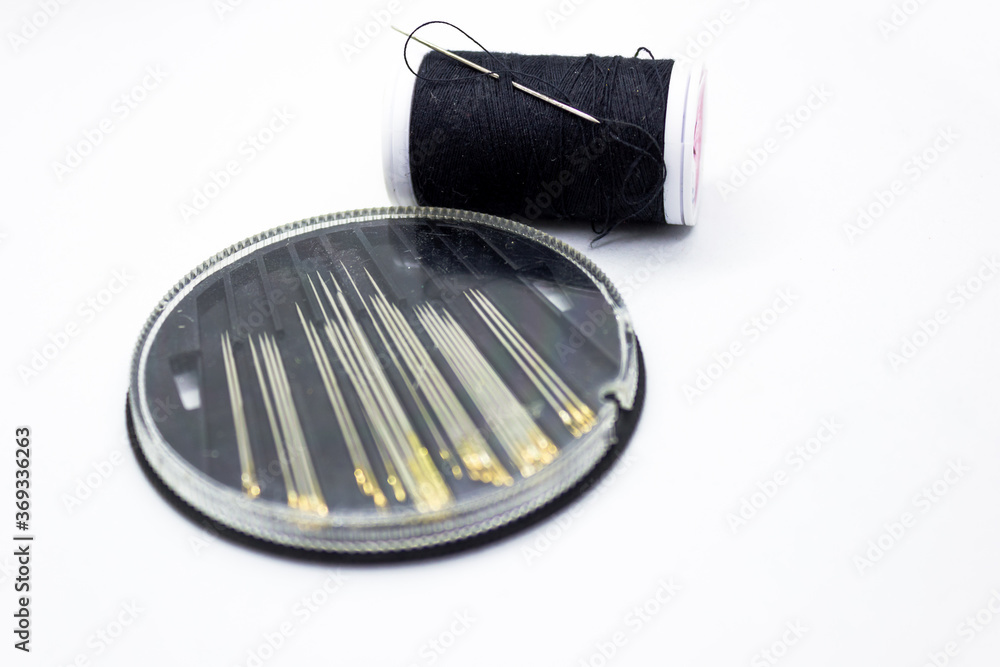 Needles and black thread for sewing against white background representing better together concept Needles and black thread for sewing against white background representing better together concept