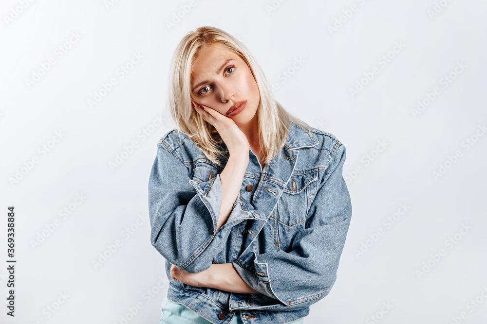 The woman thought about the choice and furrowed her eyebrows. Young beautiful blonde girl holds a hand to the face thinks and makes a decision. Place for advertising. What to choose The woman thought about the choice and furrowed her eyebrows. Young beautiful blonde girl holds a hand to the face thinks and makes a decision. Place for advertising. What to choose