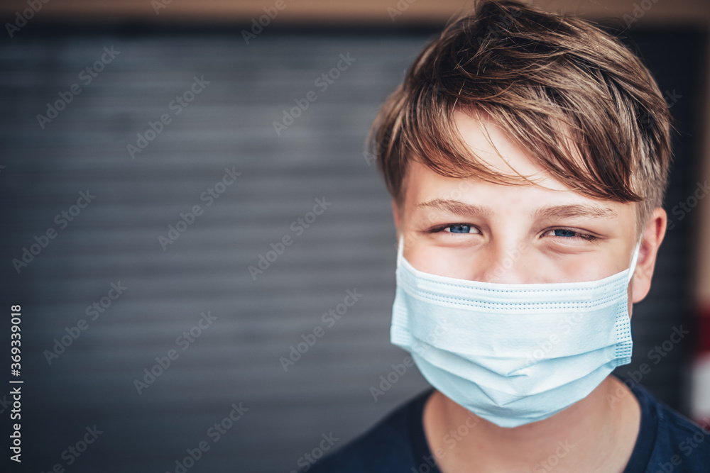 beautiful young male teenager wearing face mask required through corona pandemic