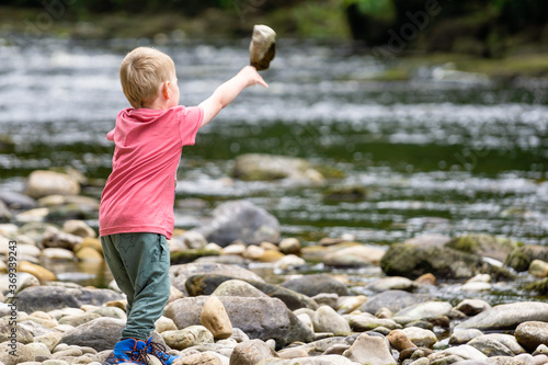 young boy throwing rock into a river