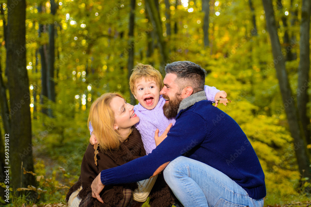 Happy smiling parents with little son in autumn park. Autumn Family. Family parenthood and people concept - happy mother father and little boy in autumn park. Happy family together in yellow nature.