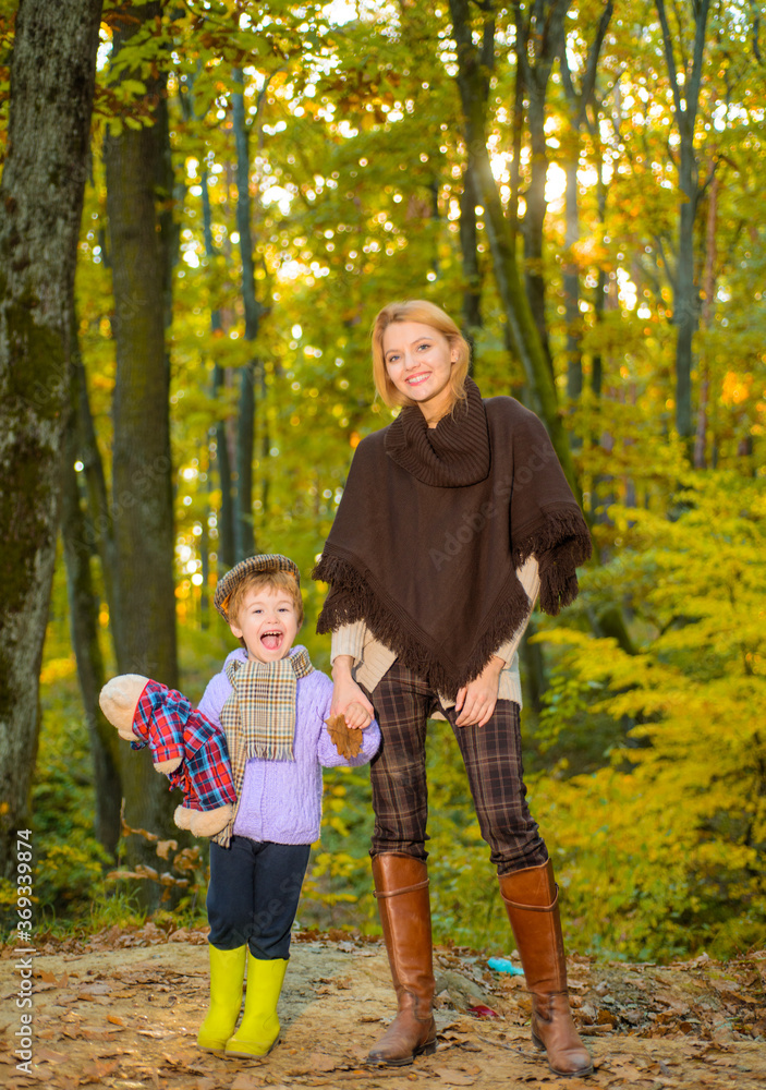 Fototapeta premium Happy mother with little son in autumn park. Autumn Family. Family parenthood and people concept - happy mother and little boy in autumn park. Happy family together in yellow nature.