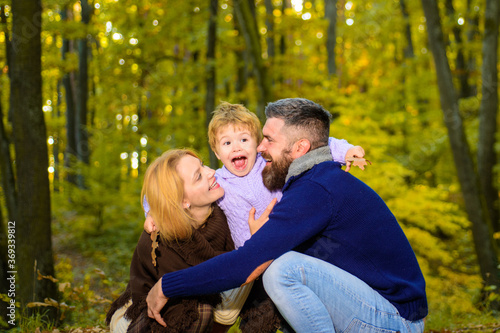 Happy smiling parents with little son in autumn park. Autumn Family. Family parenthood and people concept - happy mother father and little boy in autumn park. Happy family together in yellow nature. © Svitlana