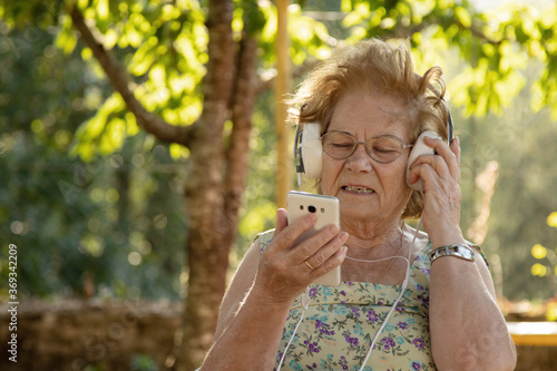 senior woman with mobile phone and headphones outdoors