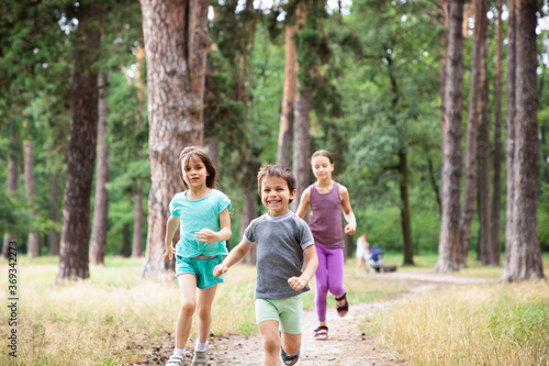 Three happy children running in forest