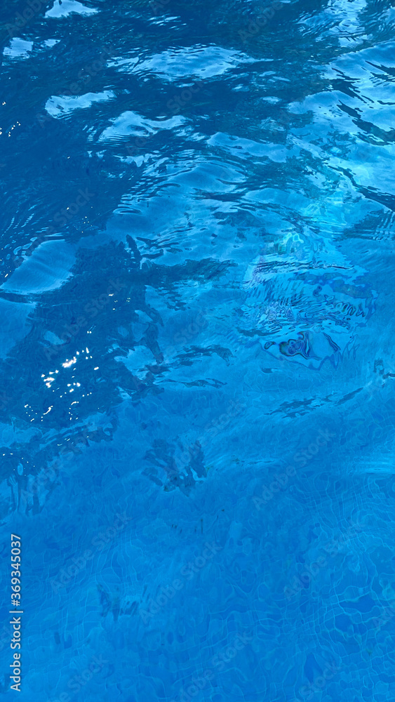 Soft focus background. Swimming pool water texture in abstract style on blue background. Ripple water. Swimming pool water sun reflection background. Summer vacation. Soft focus background. Swimming pool water texture in abstract style on blue background. Ripple water. Swimming pool water sun reflection background. Summer vacation.
