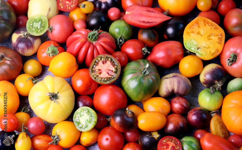 Ripe tomatoes of different shapes and colors on a wooden surface top view, selective focus.