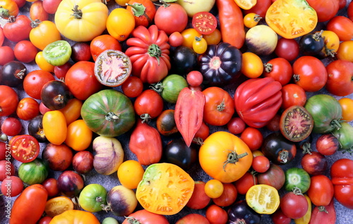 Ripe tomatoes of different shapes and colors on a wooden surface top view, selective focus.