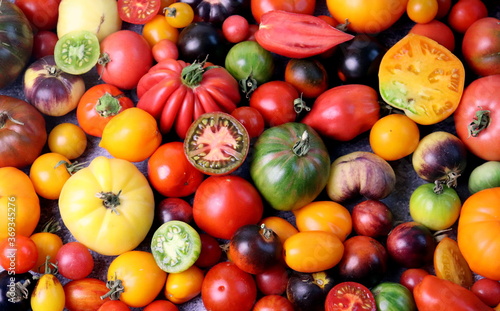 Ripe tomatoes of different shapes and colors on a wooden surface top view, selective focus.