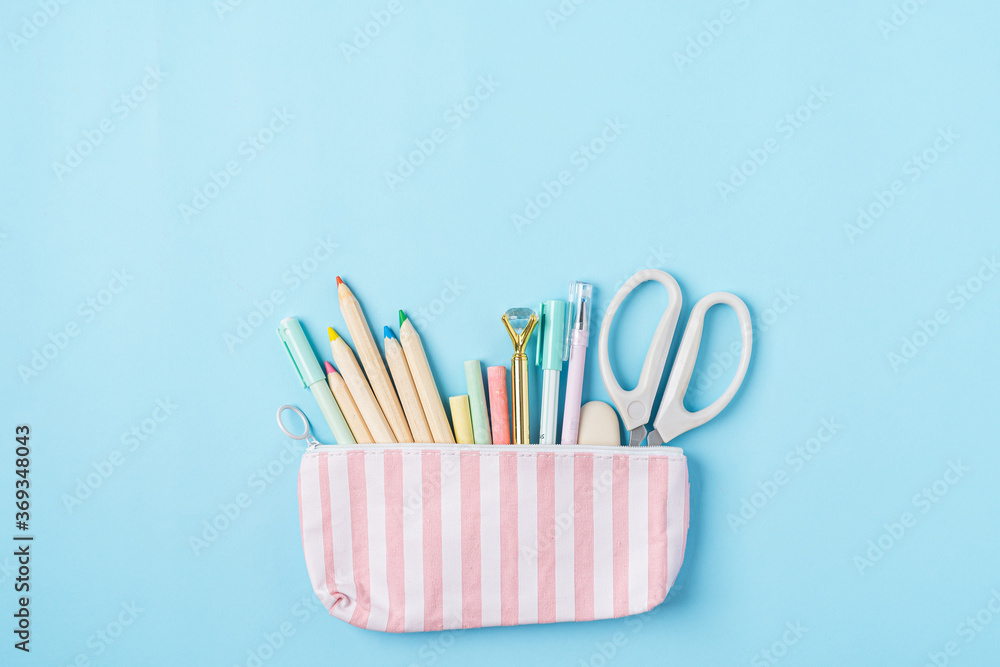 Flat lay of modern bright blue office desktop with school supplies on table around empty space for text in pencil case. Top view Back to school concept with pink scissors, pencils, pen. Flat lay of modern bright blue office desktop with school supplies on table around empty space for text in pencil case. Top view Back to school concept with pink scissors, pencils, pen.