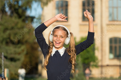 Active girl listening music modern wireless headphones while walking, dancing concept