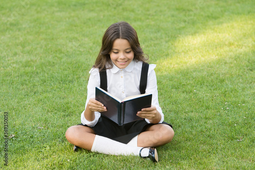 happy preschool girl with book in school yard. back to school. hardworking child with book. concept of education and reading. development of the imagination. cute girl read book
