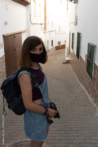 Wallpaper Mural Attractive young female wearing a face mask and carrying a reflex camera while walking through the white streets of a village in Cadiz, Spain Torontodigital.ca