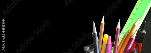 Back to school. pens, pencils, brushes in a glass against the background of a blackboard. School background with space for your text. banner