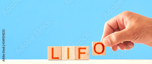 Fototapeta Naklejka Na Ścianę i Meble -  lifo. man puts wooden cubes into the word lifo on a blue background. Last in first out concept