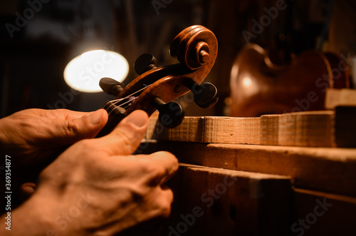 Luthier violin maker artisan setting up a violin in his workshop photo