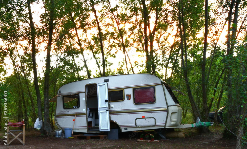Caravan trailer camping on a green lawn under a tree in springtime Caravan trailer camping on a green lawn under a tree in springtime