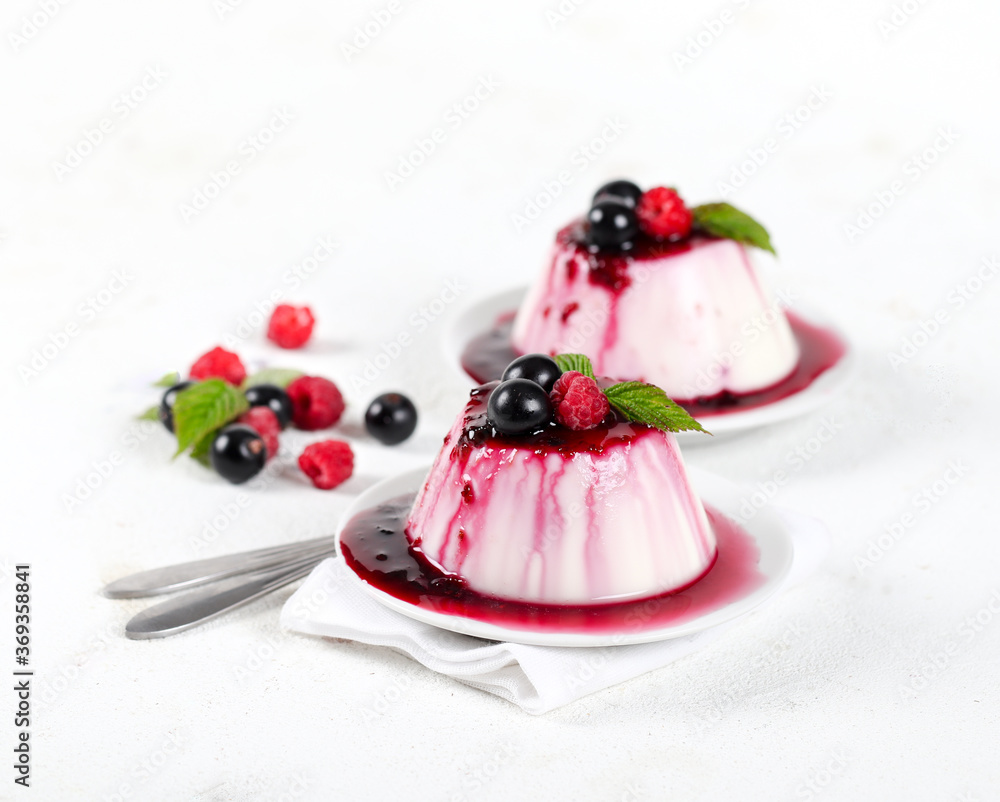 Panna cotta cream with berry sauce and fresh raspberries and black currants on a white background Panna cotta cream with berry sauce and fresh raspberries and black currants on a white background