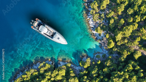 Aerial drone top down photo of inflatable speed boat anchored in tropical exotic island covered with pine trees © aerial-drone