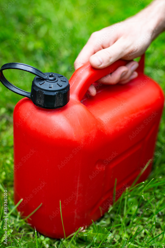 Red plastic fuel canister for a petrol lawn mower. Gardening, mowing with a gasoline lawnmower. Red plastic fuel canister for a petrol lawn mower. Gardening, mowing with a gasoline lawnmower.