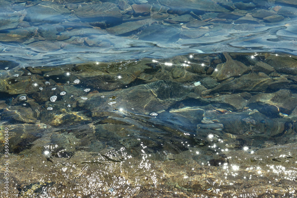 Texture of water. Abstract image of top view of shiny wave of clear sea water over sand beach, for beautiful background decoration of summer time. Game of light on the sea, sand beach . sea urchins.