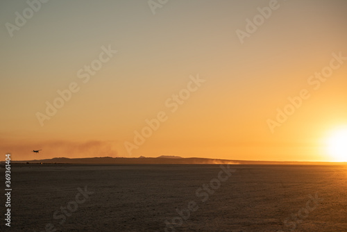 Flying private plane about to land toward the sun in the desert during sunset