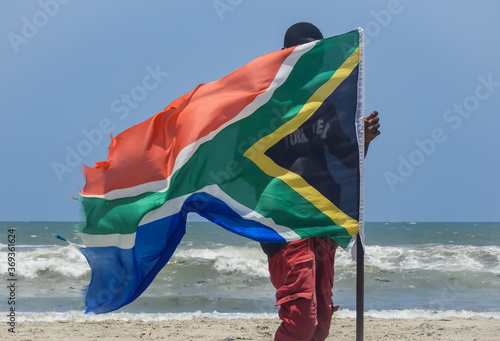 Africa Ghana man standing behind a South Africa flag on a beach in Labadi beach Accra Ghana West Africa 2018 April 16 photo