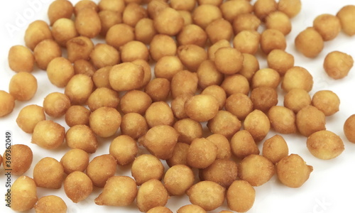 Fried batter pearls in a clay bowl. Crispy pearls. A soup topping and snack product made from flour  vegetable fat and yeast. Isolated macro food photo close up from above on white background.