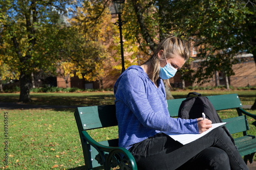 Student Wearing Mask Sitting on Park Bench