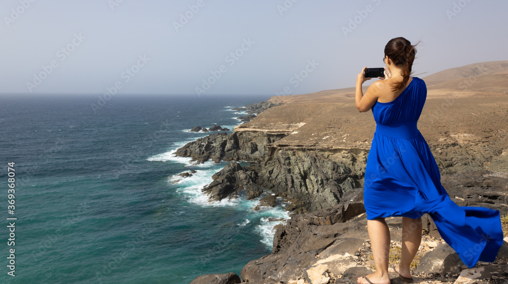 Woman takes picture on a cliff on the island of Fuerteventura - Canary Islands