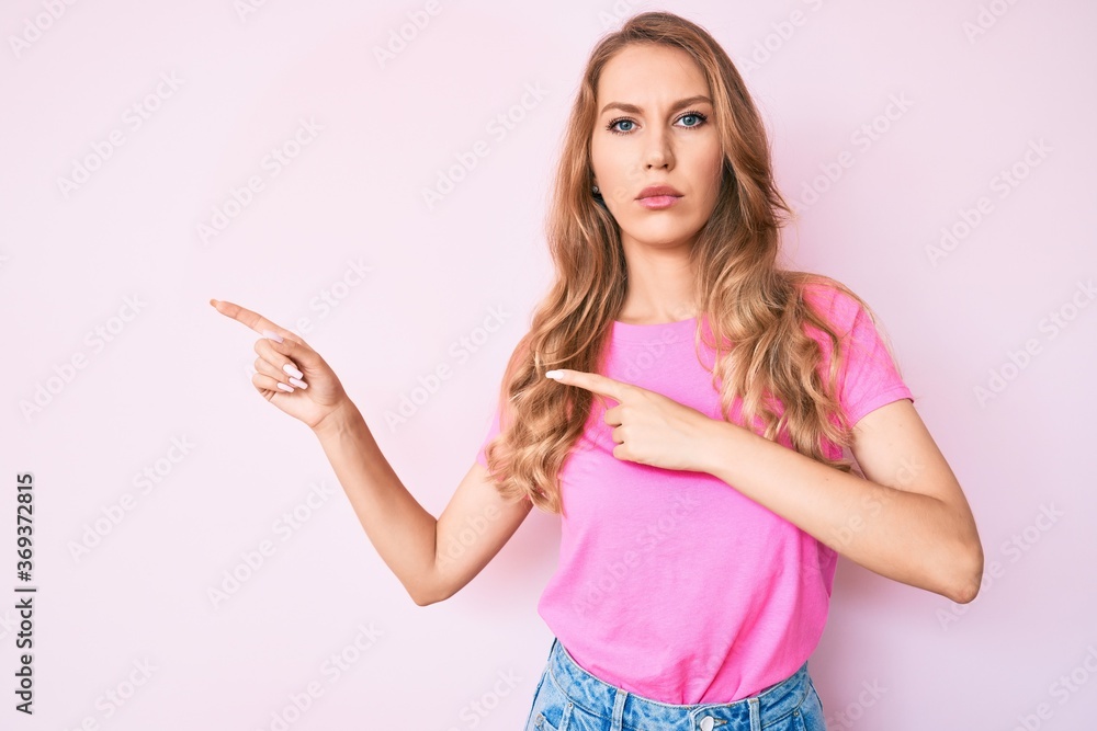 Young caucasian woman with blond hair pointing with fingers to the side skeptic and nervous, frowning upset because of problem. negative person. Young caucasian woman with blond hair pointing with fingers to the side skeptic and nervous, frowning upset because of problem. negative person.