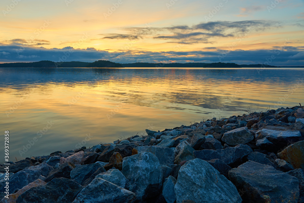 A colofrul sunset with reflections on water and granite stones on a foreground in an archipelago in Parainen, Finland.