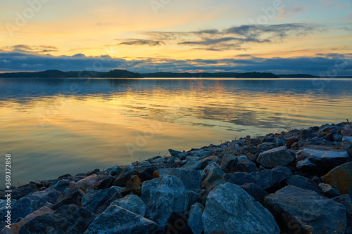 A colofrul sunset with reflections on water and granite stones on a foreground in an archipelago in Parainen, Finland.