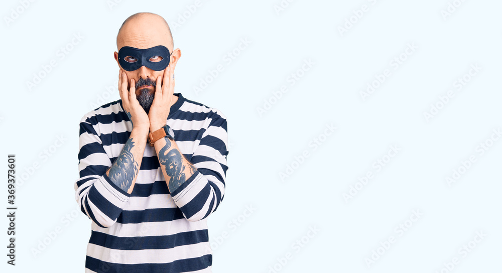 Young handsome man wearing burglar mask tired hands covering face, depression and sadness, upset and irritated for problem Young handsome man wearing burglar mask tired hands covering face, depression and sadness, upset and irritated for problem