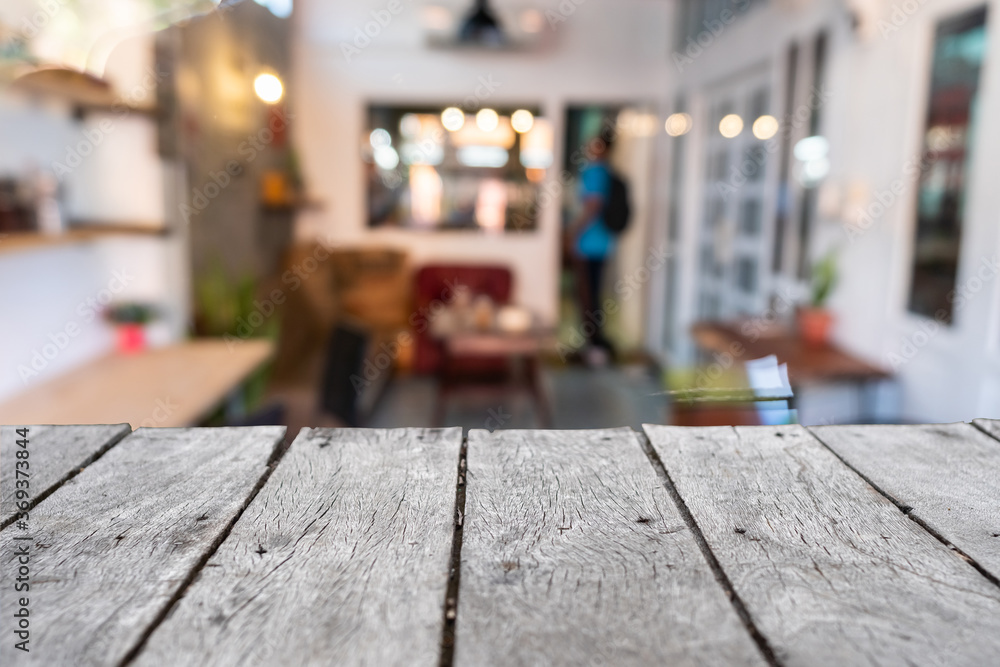 Selective focus of wooden table with blur coffee and restutant cafe with customers.