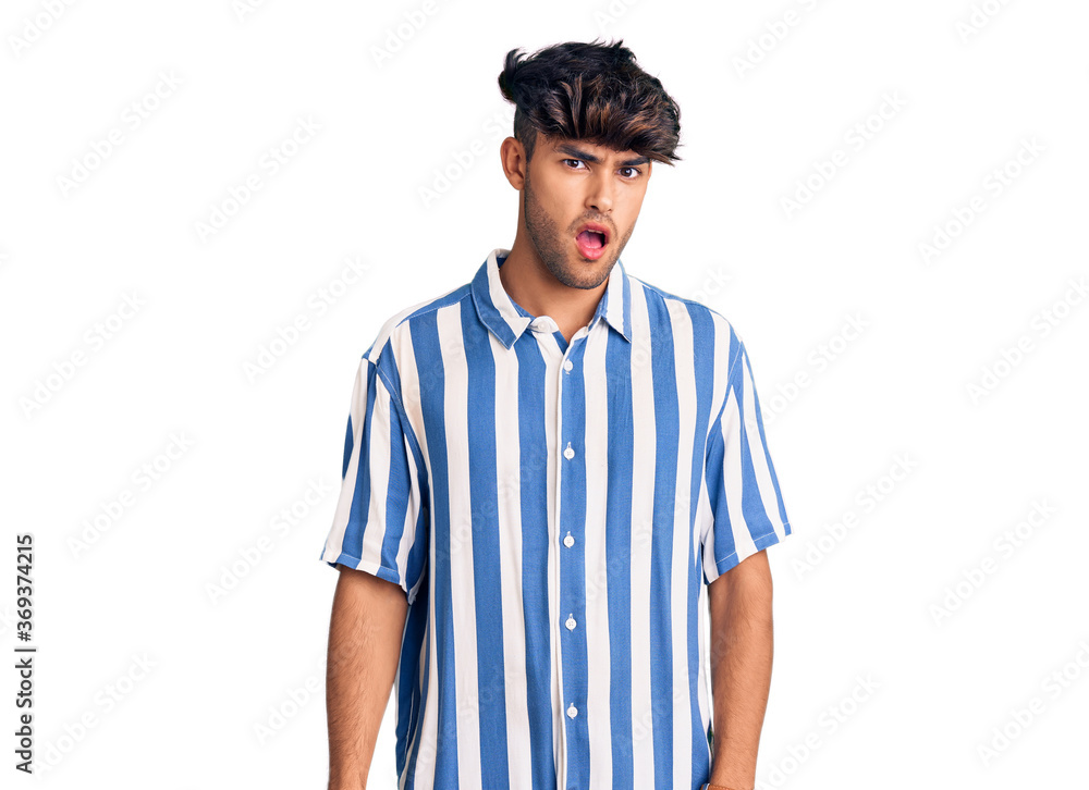 Young hispanic man wearing casual clothes in shock face, looking skeptical and sarcastic, surprised with open mouth Young hispanic man wearing casual clothes in shock face, looking skeptical and sarcastic, surprised with open mouth
