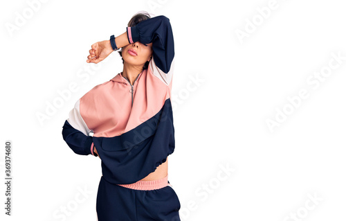 Young beautiful woman wearing sportswear covering eyes with arm, looking serious and sad. sightless, hiding and rejection concept